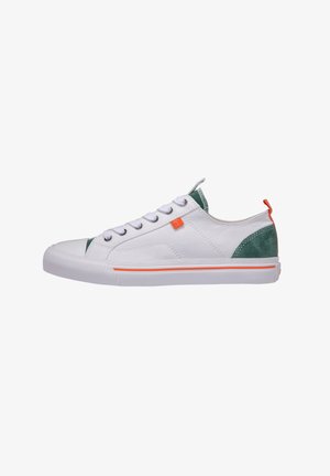 Zapatilla blanca de corte bajo con detalles de ante verde en el talón y la lengüeta, tirador naranja y franja en la suela, y cordones blancos.