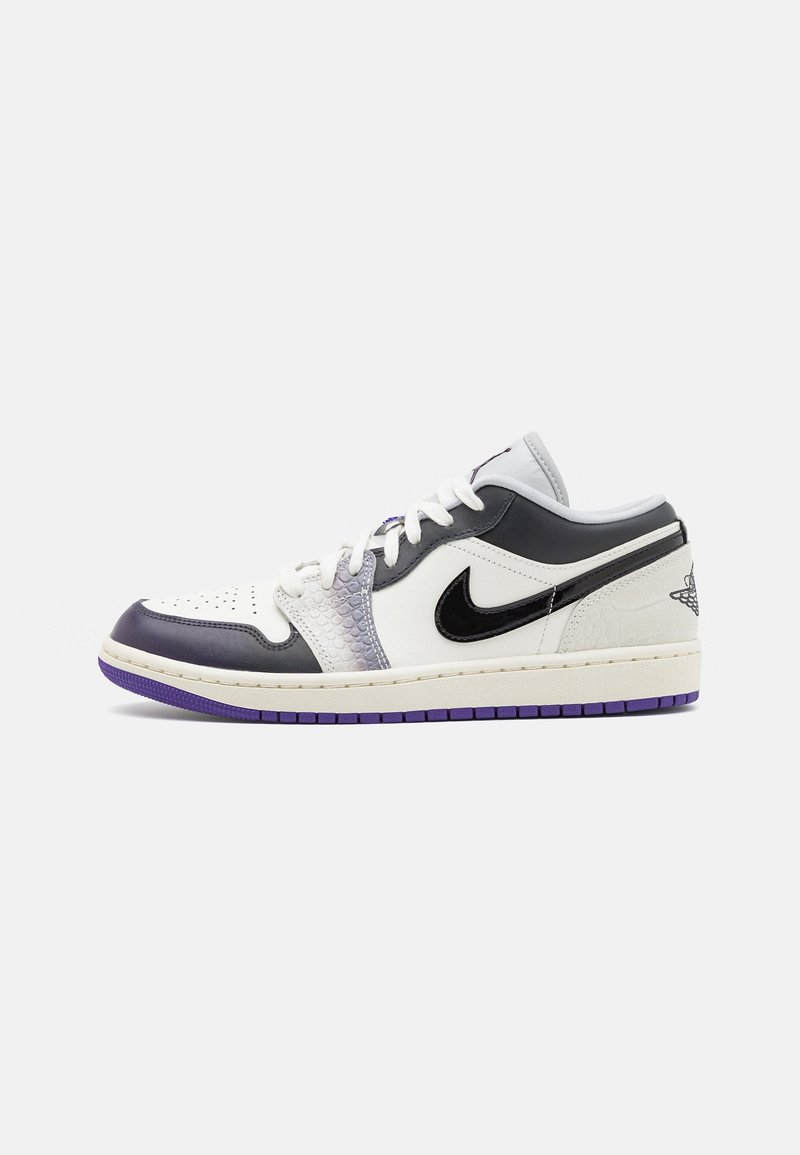 Baskets Nike basses avec des panneaux blancs, noirs et gris, texture serpent près des lacets, swoosh noir et accents de semelle violette.