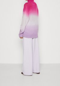 Pull surdimensionné à dégradé allant du rose au lavande, en maille texturée, associé à un pantalon large lavande pâle.