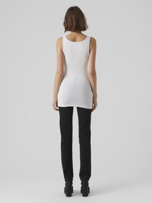 Top bianco senza maniche, design aderente con scollatura rotonda, abbinato a pantaloni neri slim-fit; tessuto leggero, texture liscia e dettagli minimi.