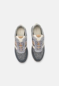 Gray and beige athletic shoes with felt and suede textures, featuring patterned laces and a rubber sole. Logo on the tongue and side.