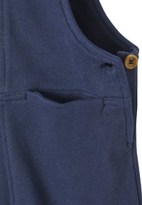 Nahaufnahme einer marineblauen Strickweste mit einer kleinen Tasche und einem braunen Knopf nahe der Schulternaht.