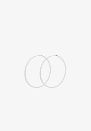 Boucles d'oreilles créoles fines en argent avec fermoirs simples et surfaces lisses et polies, présentées côte à côte sur un fond blanc.