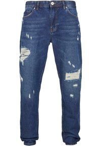 Jeans de mezclilla azul con detalle desgastado, que presentan varios desgarros y bordes deshilachados, diseño de pernera recta y estilo clásico de cinco bolsillos.