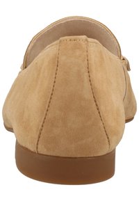 Ljust bruna mockaloafers med rund tå, låg klack och synlig söm. Bakifrån visar de en slät, minimalistisk design och mjuk textur.