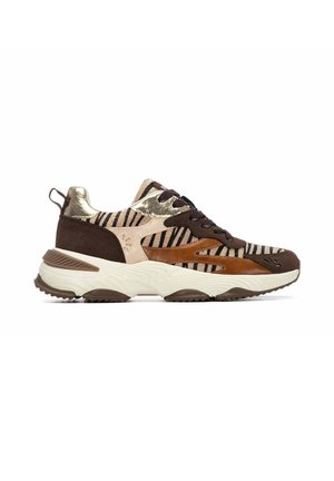 Zapatilla bulky con paneles marrones, beige y dorados metálicos, rayas negras, detalles en ante y suela blanca gruesa.