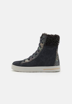 Black suede ankle boot featuring a textured, fur-lined collar and multicolored floral pattern on the side, with a light-colored sole.
