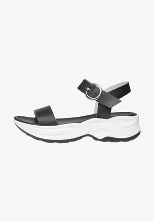 Sandale ouverte en cuir noir avec boucle de sangle réglable à la cheville et semelle contournée blanche épaisse, vue de côté.
