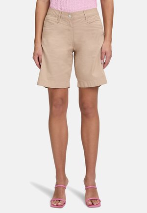 Shorts en coton beige avec une coupe décontractée, ourlet replié et deux poches avant. Assortis à des sandales roses à lanières.