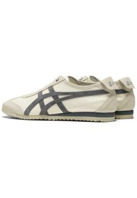 Mannensneakers van crème leer met donkergrijze suède accenten en veters. Heeft een gestructureerde zool en een laag profiel ontwerp.