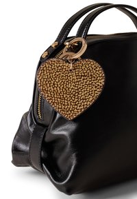 Black leather handbag with gold hardware, featuring a textured brown heart-shaped charm. Smooth surface and gathered design.