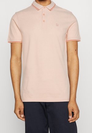 Koszulka polo w jasnym brzoskwiniowym kolorze z plisą na dwa guziki, kontrastującym pomarańczowym żebrowanym kołnierzykiem i mankietami na rękawach, z małym logo na piersi.