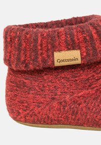 Strikket uldsko i nuancer af rød og brun med en fold-over manschet og en læderlap mærket "Gottstein." Glat såldesign.