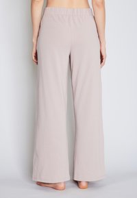 Helle beige weit geschnittene Hose mit elastischem Bund, aus weichem Stoff gefertigt. Sie hat eine lockere Passform und keine sichtbaren Muster oder Akzente.