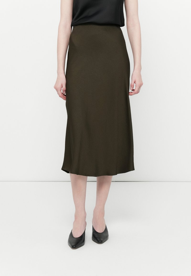 Jupe midi vert olive en tissu lisse avec un léger éclat, dotée d'une taille cintrée et d'une silhouette évasée, accompagnée de talons noirs.