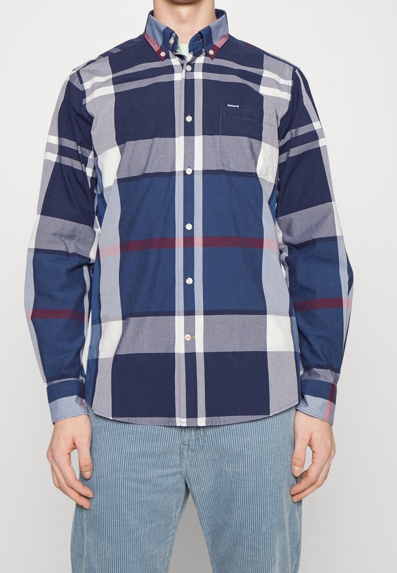 Geruit overhemd met knopen in marineblauw, grijs en wit met rode accenten. Katoenen stof, lange mouwen en een borstzakje.