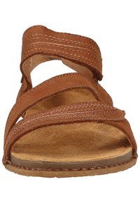 Hnědá sandál s křížovým popruhovým designem, vyrobená z texturované kůže, disponující polstrovanou stélkou a gumovou podrážkou, vhodná pro každodenní nošení.