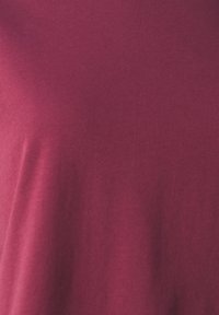 Bordeaux bomulls T-skjorte med glatt tekstur og enkel rund hals-design, med en tilpasset silhuett og minimal detaljering.
