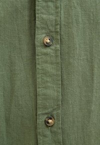 Groene linnen shirt met een verticale knoopsluiting met bruine knopen en een licht gestructureerde stof.
