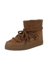 Zapatillas marrones de caña baja con parte superior de ante, cordones texturizados y suela plana de goma. El diseño tiene una estética minimalista.