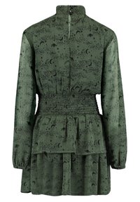 Zielona sukienka z długim rękawem i wysokim kołnierzem, z marszczonym pasem i gwiaździstym wzorem w kolorze czarnym. Zapięcie na guziki z tyłu.