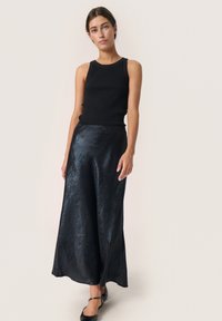 Sort ribbet tanktop parret med en lang, flydende, shiny sort satin nederdel, der har en glat tekstur og en let glans.