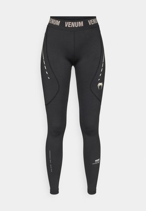 Czarne legginsy z wysokim pasem, z logo VENUM, zakrzywionymi szwami oraz lekkimi dekoracyjnymi liniami po zewnętrznych stronach.
