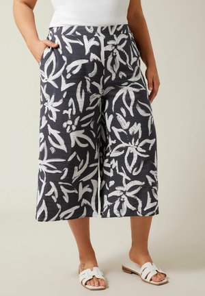 Culotte-style trousers in navy with white floral print, featuring side pockets and a lightweight woven texture. Flat waistband, knee-length cut.