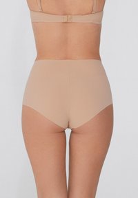Beżowe, wysokie majtki wykonane z gładkiego, elastycznego materiału. Bezszwowa konstrukcja i miękka tekstura zapewniają komfort oraz dyskrecję pod odzieżą.