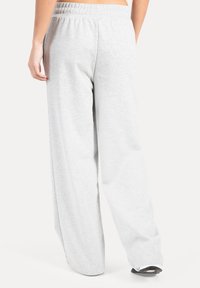 Pantalones de chándal de pierna ancha en gris claro, con cinturilla elástica y tela suave y texturizada, que presentan un ajuste holgado.