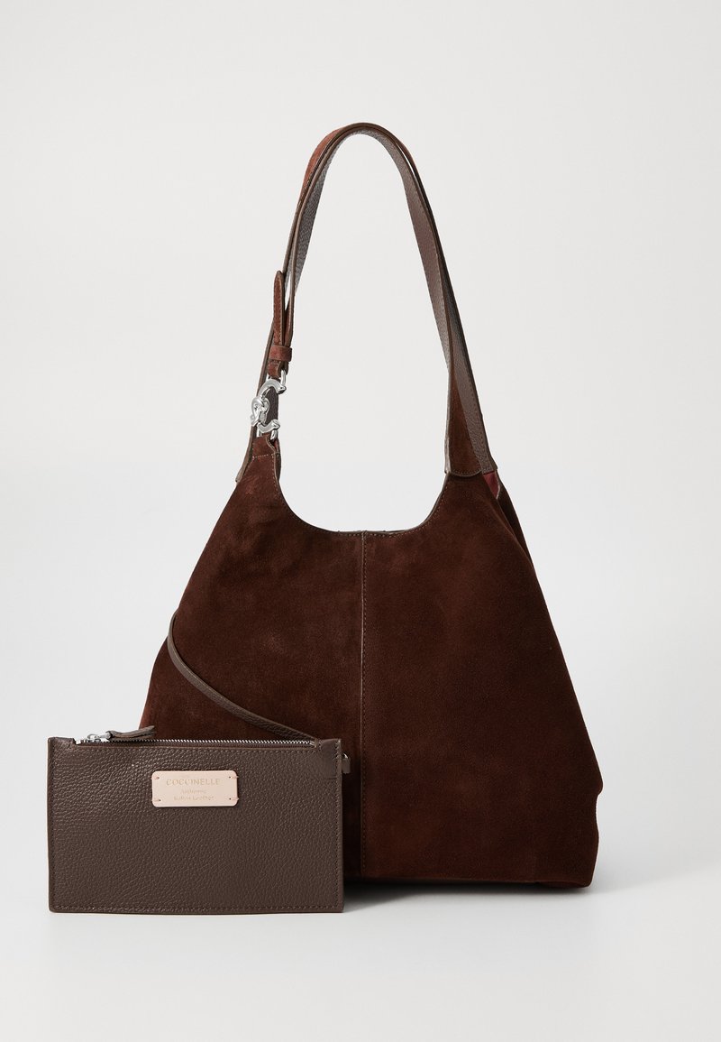 Brown suede hobo bag with a shoulder strap, featuring a textured brown leather pouch with a gold-tone brand tag. Soft, curved shape.
