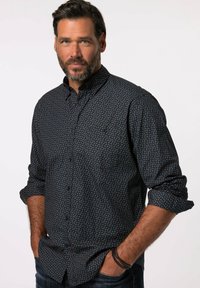 Marineblaue Button-up-Bluse mit einem subtilen Muster aus kleinen orangefarbenen abstrakten Formen, lange Ärmel hochgerollt und mit zwei vorderen Taschen.