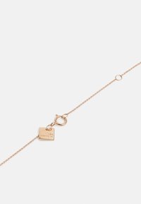 Pulsera de cadena de oro rosa de 18 quilates con una etiqueta rectangular que presenta el grabado "GINETTE NY" y un cierre de langosta redondo.