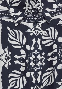 Camicia a righe navy e bianca con un design floreale tradizionale, colletto a punta e chiusura frontale con bottoni, realizzata in tessuto morbido.