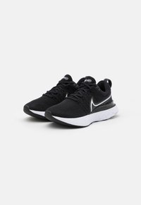 Zapatillas deportivas negras con un upper texturizado, acentos blancos en el costado y la suela, que cuentan con una suela acolchada y un diseño seccional.