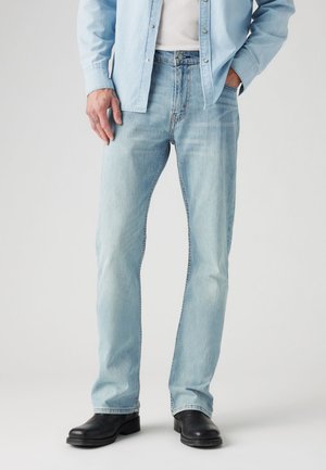 Light blue denim jeans with a straight leg design, subtle fading, and classic five-pocket styling, paired with black leather boots.