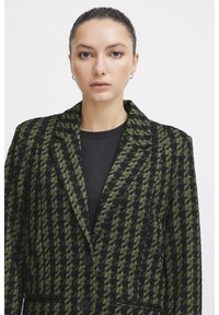 Černý a zelený kostkovaný blazer se strukturovaným designem, klopovými límci a dvěma knoflíky, s texturovanou tkaninou a bočními kapsami.