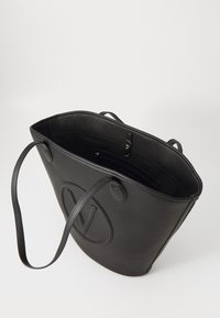 Schwarze Leder-Tote-Tasche mit strukturierter Oberfläche, großem Hauptfach, langen Griffen und einem geprägten Logo auf der Vorderseite.