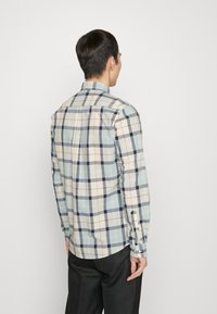 Langsleeve geruite shirt in een combinatie van lichtblauw, beige en marineblauw. Frisse katoenen stof met knoopmanchetten en een klassieke kraag.