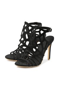 Schwarze High Heels Sandalen mit einem ausgeschnittenen Design, aus glattem Material gefertigt, mit einem Riemen um den Knöchel und einer spitzen Zehe.