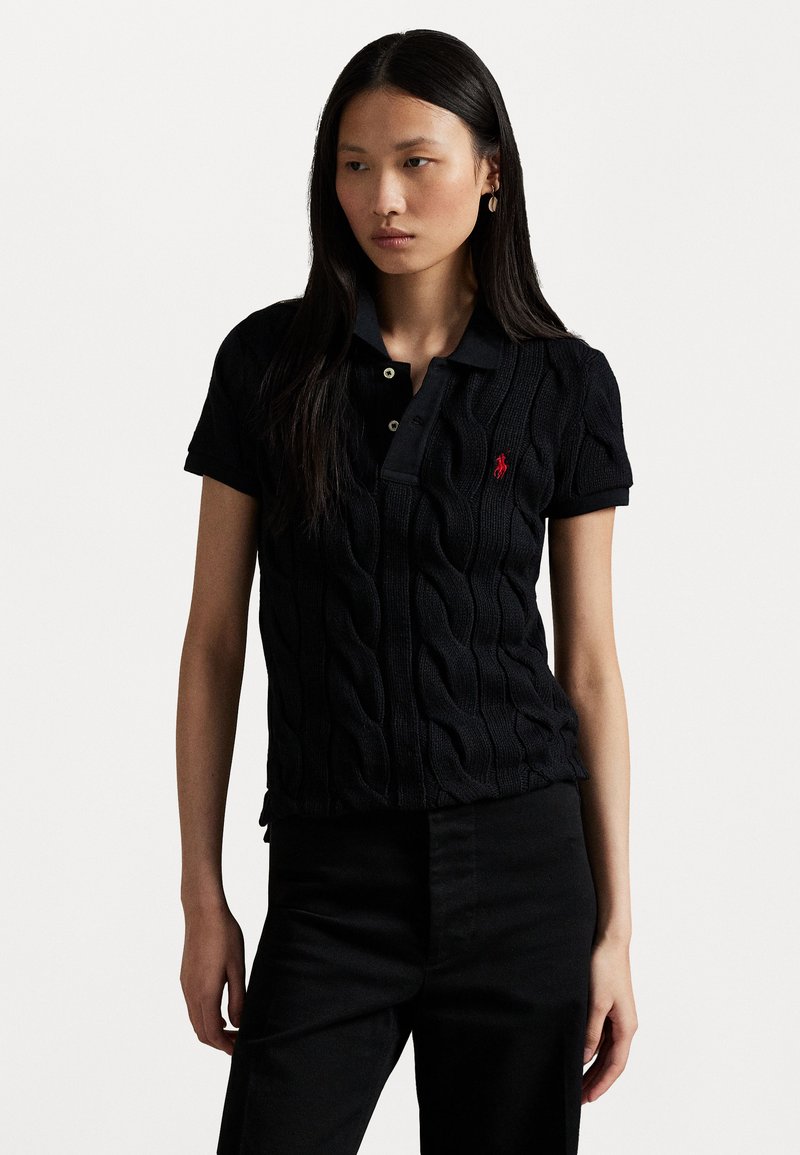 Black knitted polo shirt with cable pattern, short sleeves, and a collar. Features a small red logo on the left chest.
