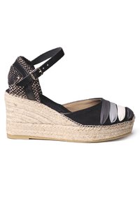 Espadrille cuña negra con parte superior de tela trenzada y correa negra. Presenta bandas de tela gris y blanca en la parte delantera y suela envuelta en yute.