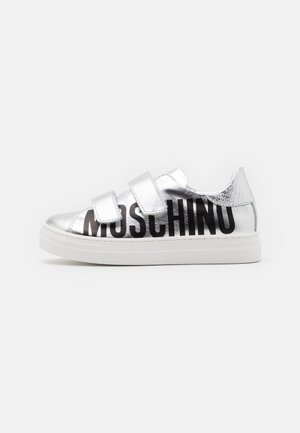 Zapatillas plateadas con tiras de Velcro, atrevido logotipo en negro "MOSCHINO", detalles texturizados y suela de goma blanca.