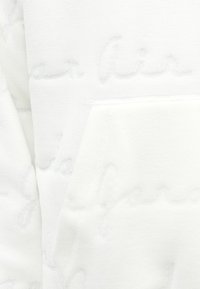 Sweat-shirt blanc avec un design texturé et des lettrages embossés. Il comprend une poche avant et une finition douce et polaire.