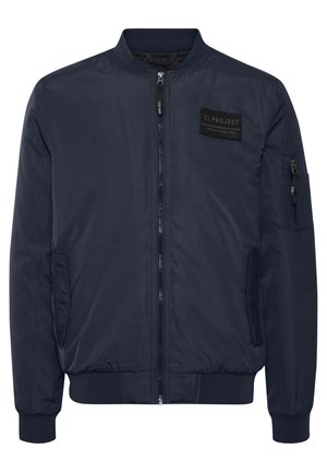 Jachetă de bombardier navy, fabricată dintr-un material neted. Include un fermoar frontal, buzunare laterale și un ecuson pe partea superioară stângă. Manșete și tiv ribbate.