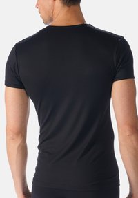 Zwarte T-shirt met korte mouwen, gemaakt van soepel, rekbaar materiaal. Fitted ontwerp met een ronde hals en minimale naden, die een slanke silhouet benadrukt.