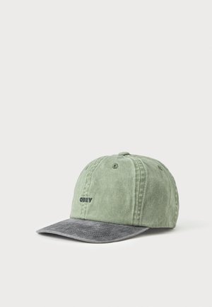 Gorra de béisbol verde de tela con una visera curva gris y pequeño texto negro "OBEY" en el lado delantero izquierdo.