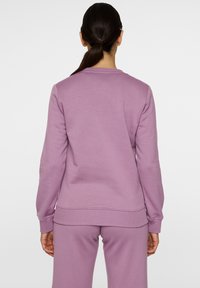 Felpa viola chiaro realizzata in tessuto morbido, con polsini e orlo a coste, dalla vestibilità comoda e colletto rotondo. Visualizzazione della vista posteriore.