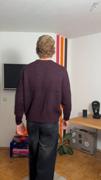 Dunkellila Strickpullover mit lockerem Schnitt, rundem Ausschnitt und langen Ärmeln, kombiniert mit schwarzer Hose. Von hinten gesehen.