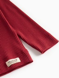 Maglietta a maniche lunghe rossa a coste con un tessuto testurizzato. L'etichetta sull'orlo riporta "Marmar Copenhagen." Vestibilità standard con scollatura rotonda.